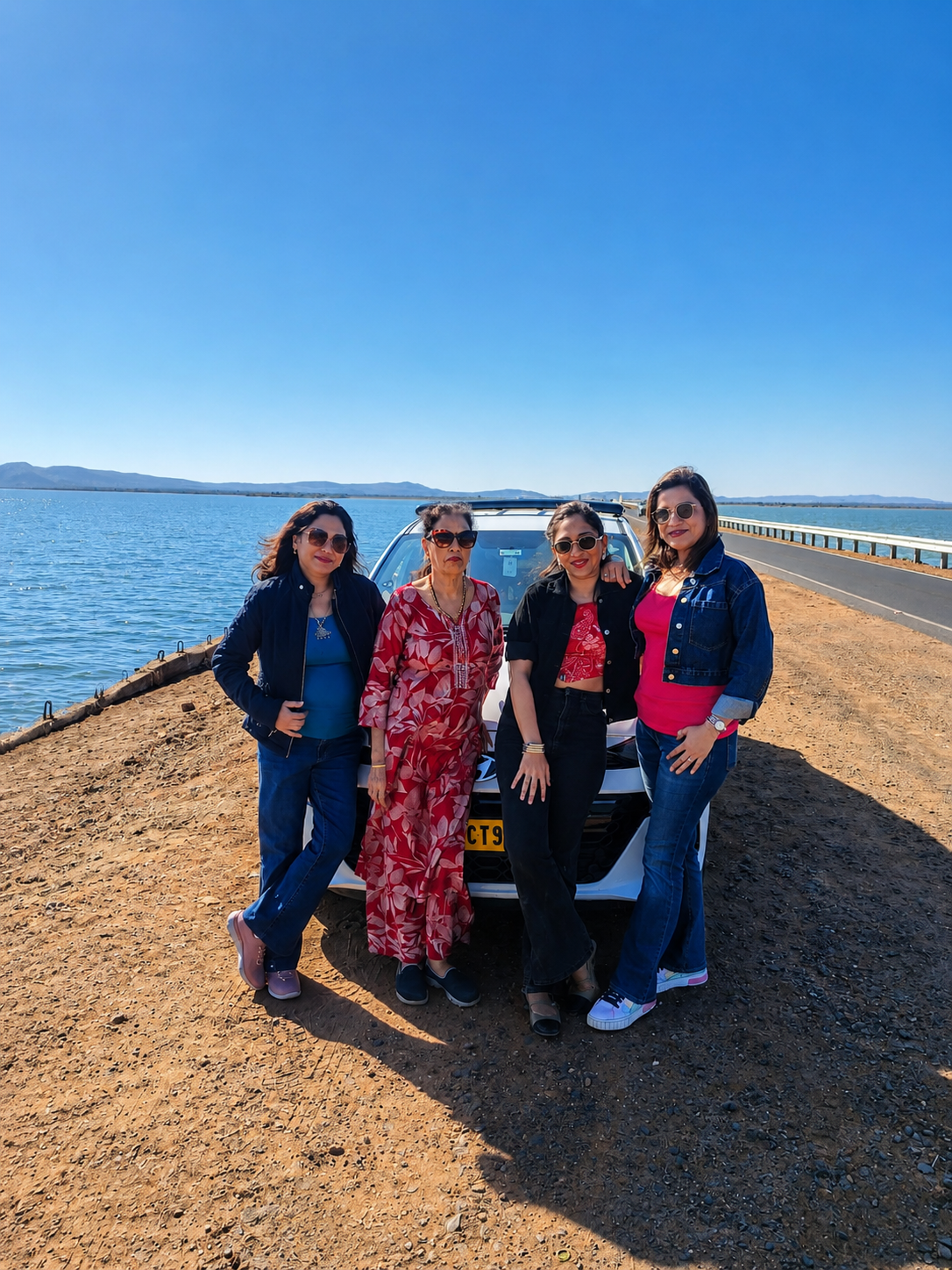Friends enjoying a scenic Gujarat road trip beside their car
